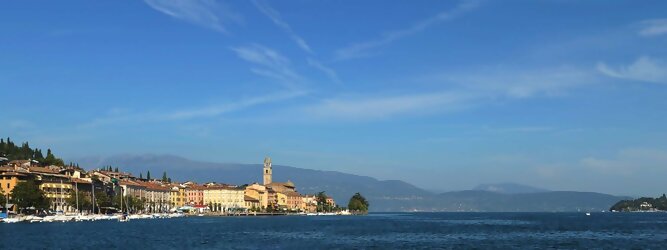 Städtereisen beliebte Urlaubsziele am Gardasee -  Mit einer Fläche von 370 km² ist der Gardasee der größte See Italiens. Es liegt am Fuße der Alpen und erstreckt sich über drei Staaten: Lombardei, Venetien und Trentino. Die maximale Tiefe des Sees beträgt 346 m, er hat eine längliche Form und sein nördliches Ende ist sehr schmal. Dort ist der See von den Bergen der Gruppo di Baldo umgeben. Du trittst aus deinem gemütlichen Hotelzimmer und es begrüßt dich die warme italienische Sonne. Du blickst auf den atemberaubenden Gardasee, der in zahlreichen Blautönen schimmert - von tiefem Dunkelblau bis zu funkelndem Türkis. Majestätische Berge umgeben dich, während die Brise sanft deine Haut streichelt und der Duft von blühenden Zitronenbäumen deine Nase kitzelt. Du schlenderst die malerischen, engen Gassen entlang, vorbei an farbenfrohen, blumengeschmückten Häusern. Vereinzelt unterbricht das fröhliche Lachen der Einheimischen die friedvolle Stille. Du fühlst dich wie in einem Traum, der nicht enden will. Jeder Schritt führt dich zu neuen Entdeckungen und Abenteuern. Du probierst die köstliche italienische Küche mit ihren frischen Zutaten und verführerischen Aromen. Die Sonne geht langsam unter und taucht den Himmel in ein leuchtendes Orange-rot - ein spektakulärer Anblick.